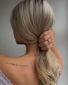 the back of a woman's head with a tattoo on her left shoulder