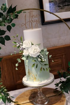 a three tiered cake with white flowers and greenery