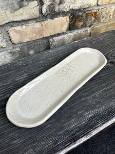 a white ceramic dish sitting on top of a wooden table next to a brick wall