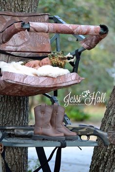 a baby sleeping in a stroller next to a tree with boots on the ground