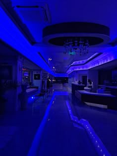 an indoor swimming pool lit up with blue lights and chandelier hanging from the ceiling