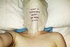 a man laying in bed with a sheet covering his face that says what a flammarble heart we been given