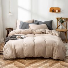 a bed in a room with wooden floors and white walls, along with an area rug that has chevron wood flooring