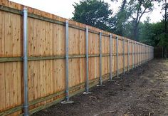 a wooden fence is lined with metal posts