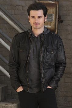 a man standing in front of some stairs with his hands in his pockets and looking at the camera