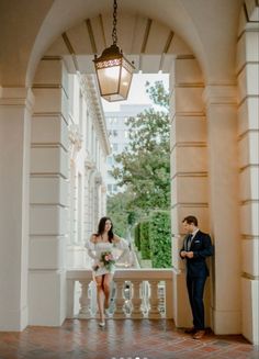 a man standing next to a woman in front of a light fixture on a balcony