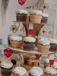 cupcakes with white frosting and red hearts on top are arranged in the shape of a tower