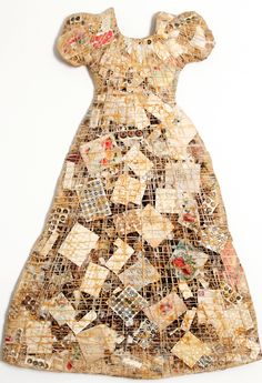 an old dress made out of fabric with small squares and flowers on the front, sitting on a white surface