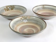 three small bowls with designs on them sitting next to each other in front of a white background