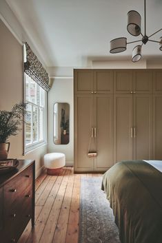 a bedroom with wooden floors and large closets in it's center, next to a bed