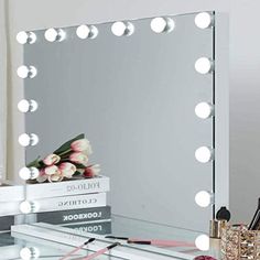 a vanity mirror sitting on top of a table next to a vase with flowers and makeup