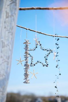 a star mobile hanging from a tree branch with beads and stars attached to the strings