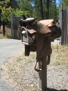 a horse saddle is attached to a post by a fence and some trees in the background