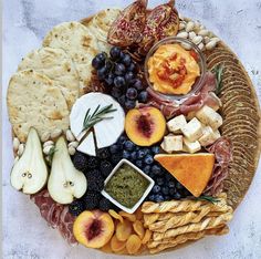 an assortment of cheeses, crackers and fruit on a platter