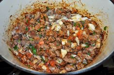 meat and vegetables cooking in a pan on the stove