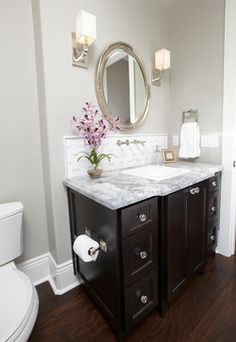 a white toilet sitting next to a sink in a bathroom under a large round mirror