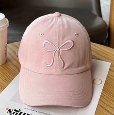 a pink hat sitting on top of a wooden table next to a cup of coffee