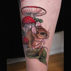 a tattoo on the leg of a person with a mouse in front of a mushroom