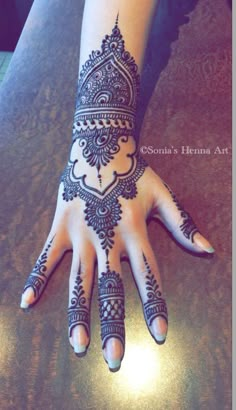 a woman's hand with henna tattoos on it