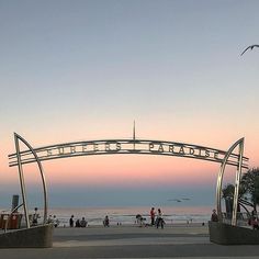 people walking on the beach at sunset under an arch that reads,'welcome to atlantic city '