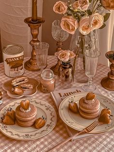 a table topped with plates and cups filled with desserts on top of a checkered table cloth