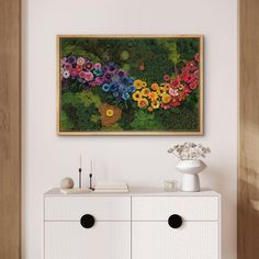 a white dresser topped with drawers next to a painting