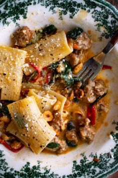 a plate filled with pasta and meat on top of a wooden table next to a fork