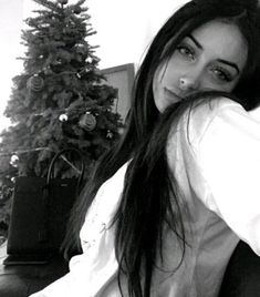 black and white photograph of a woman sitting in front of a christmas tree with her hand on her head