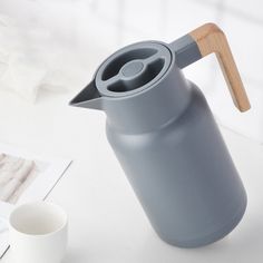 a gray coffee pot sitting on top of a white table