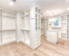 an empty walk in closet with white cabinets