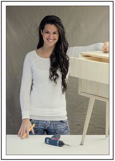 a woman standing next to a table with a drill