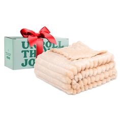 a stack of folded towels next to a box with a red ribbon on it and a bow