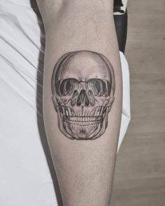 a man's arm with a skull tattoo on the left side of his leg