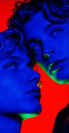 two men are looking at each other with blue and red lighting on their faces in front of them