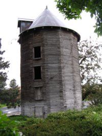 an old round building with a white roof in the middle of some bushes and trees