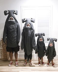 three adults and two children in shark costumes standing next to each other with their mouths open