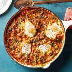 two fried eggs are in a skillet with tomato sauce and parmesan cheese