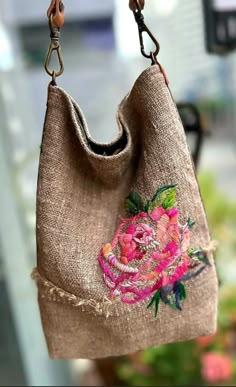 a purse hanging from a hook on a window sill with flowers painted on it