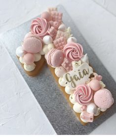 a cake decorated with pink and white icing on top of a gray plate that says gaia