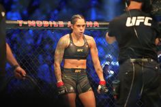 a female fighter standing in front of a fence