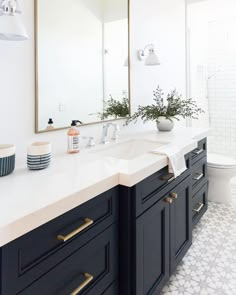 a white and black bathroom with two mirrors on the wall next to it's double sinks