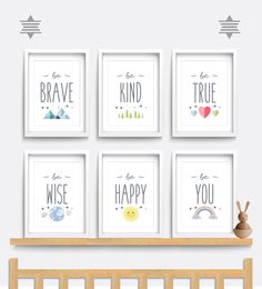 four framed art prints on a wall above a crib