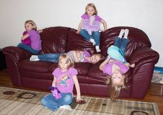 four children are laying on the couch and one is lying down with her legs up