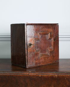 an old wooden box sitting on top of a brown table next to a white wall