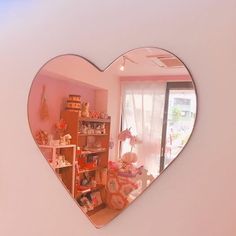 a heart shaped mirror hanging on the side of a wall next to a shelf filled with stuffed animals