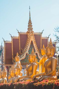 golden buddha statues sitting in front of a building