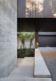 an entrance to a modern house with concrete walls and trees in the backround