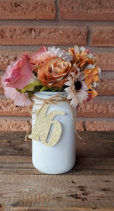 a white mason jar filled with flowers on top of a wooden table