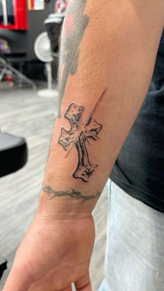 a man with a cross tattoo on his arm