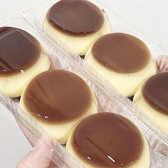 there are four cookies with chocolate on them in the plastic container, and one is being held by someone's hand